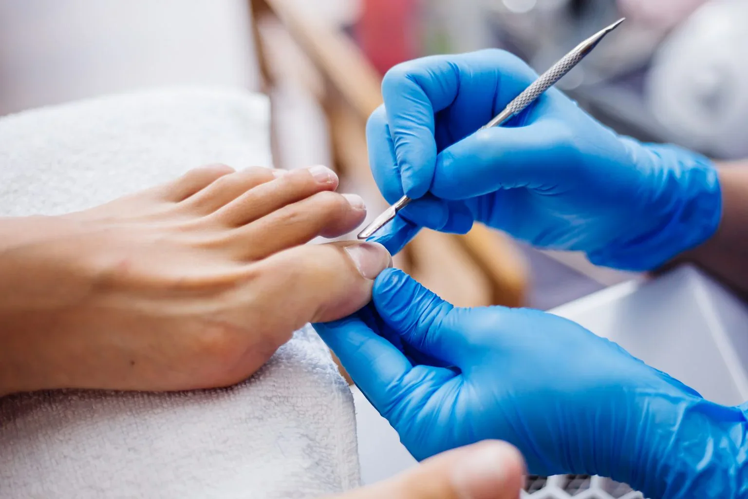 Profissional com luvas realizando o cuidado das unhas dos pés